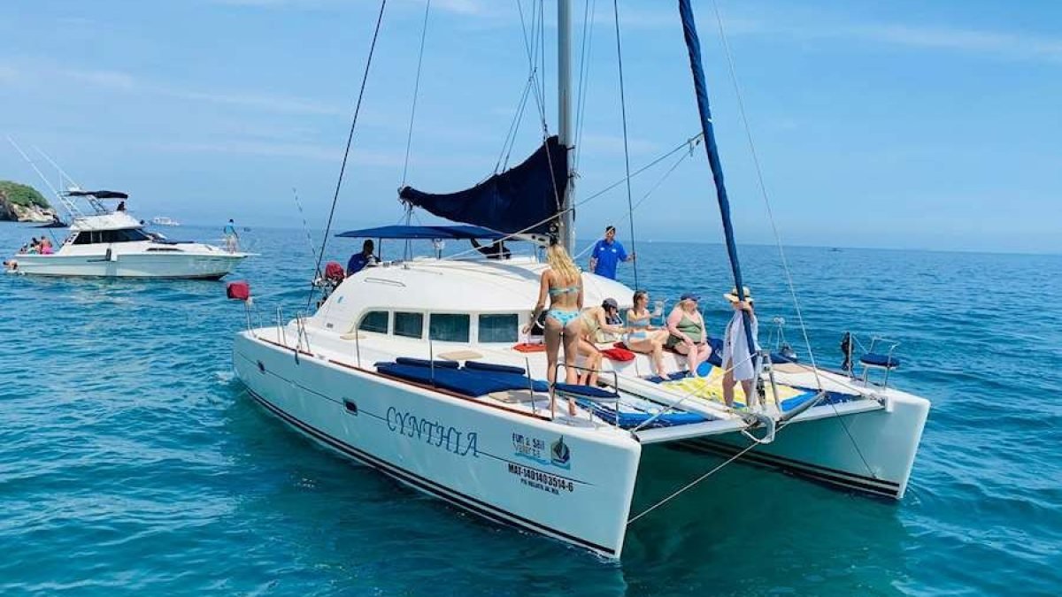 Guests swimming and sunbathing on a Lagoon 38 catamaran anchored in calm water during a private yacht charter on Banderas Bay