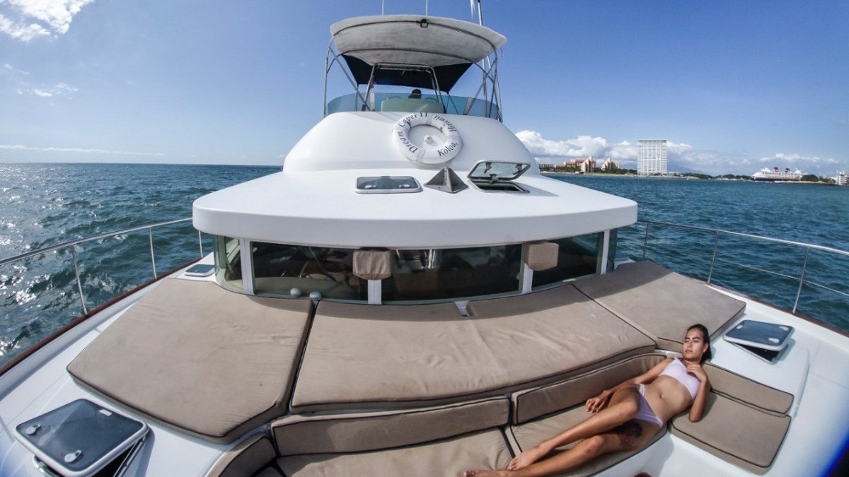 Guest relaxing on the padded bow lounge of a power catamaran during a private yacht charter on Banderas Bay, Riviera Nayarit
